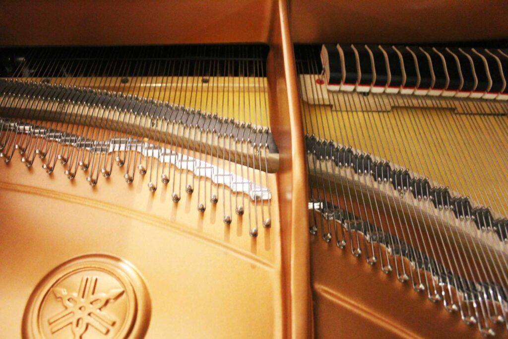 Cuerdas agudas del interior de un piano de cola Yamaha